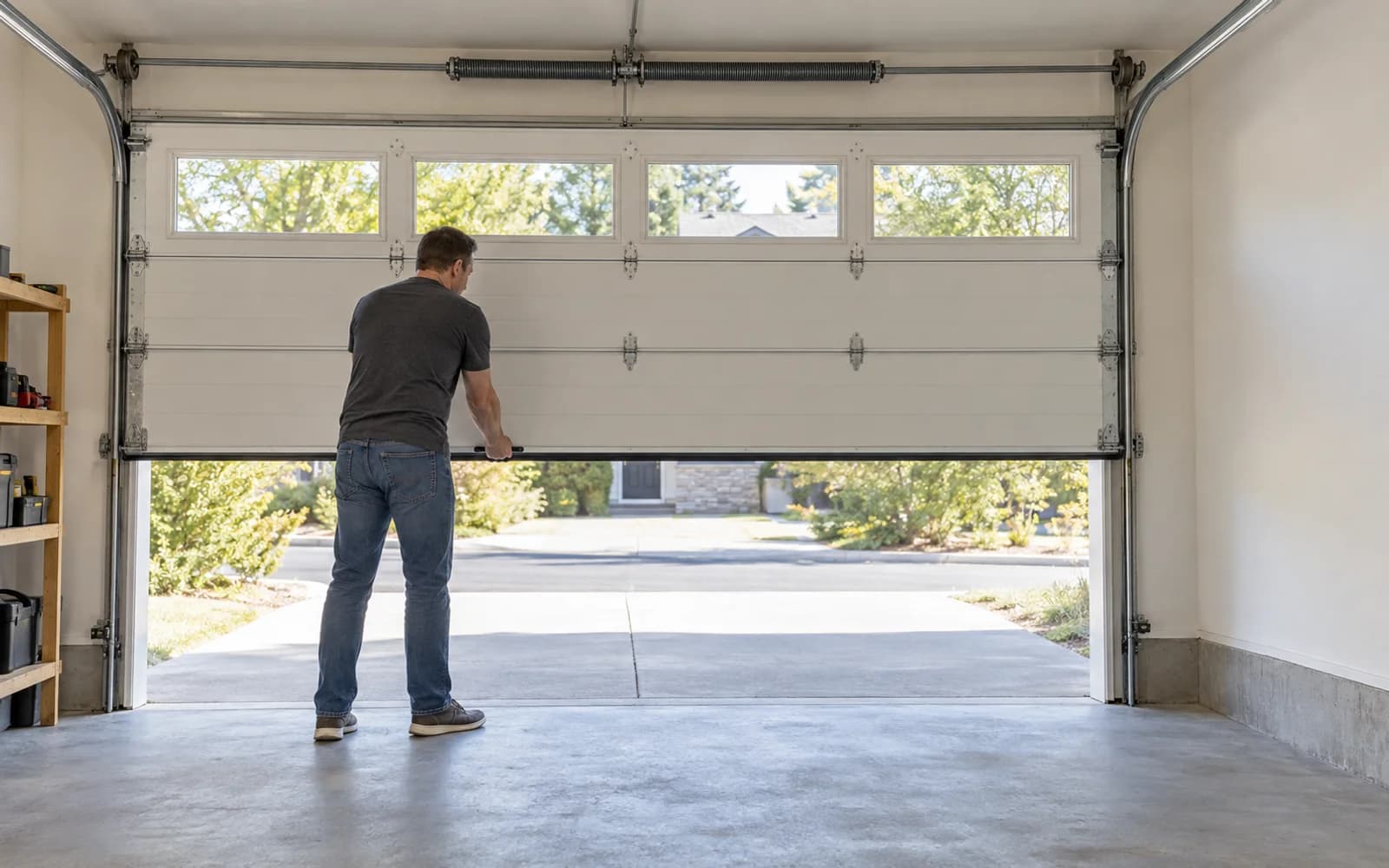 A person lifts the door manually inside a garage without an electric opener.